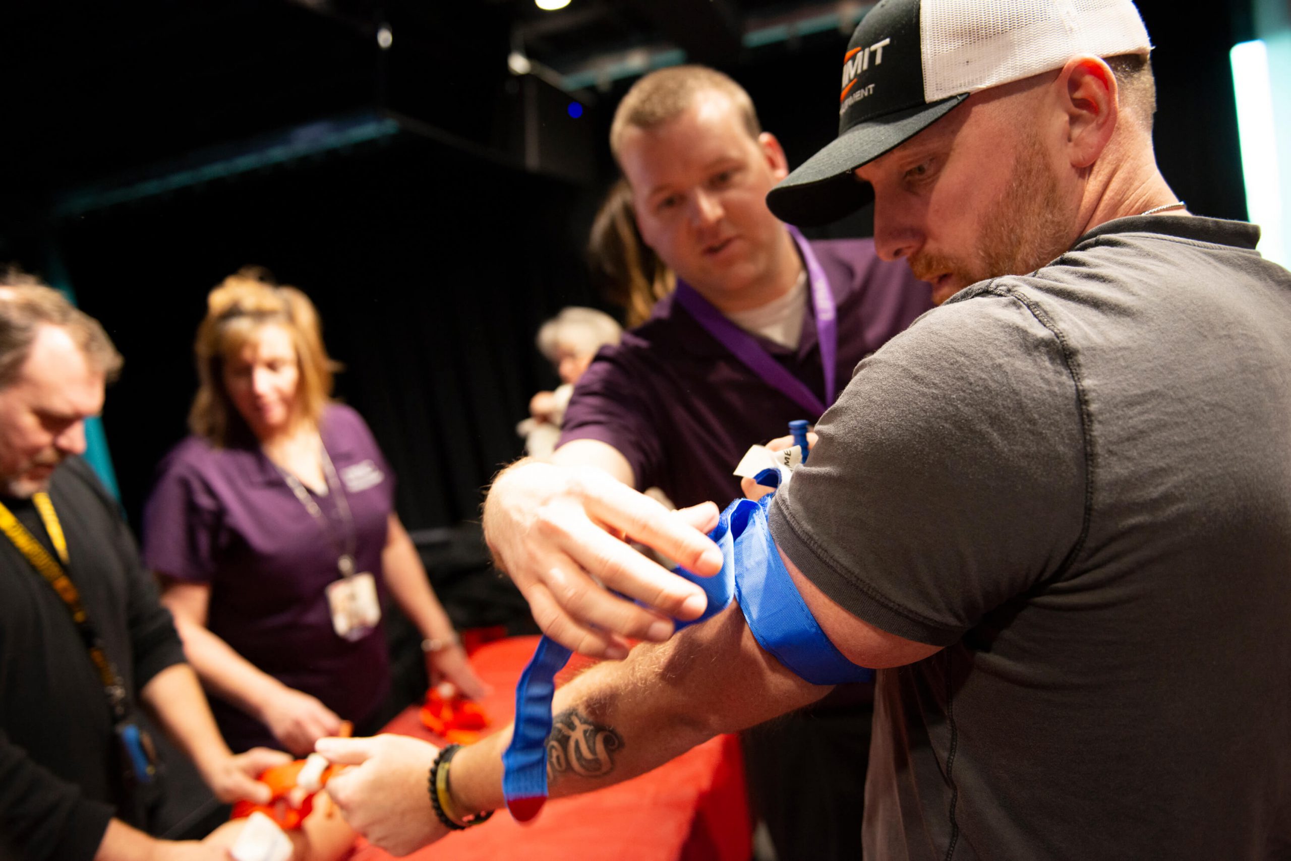 Man adjusting an arm band to teach life saving techniques at an iHeartRadio event.