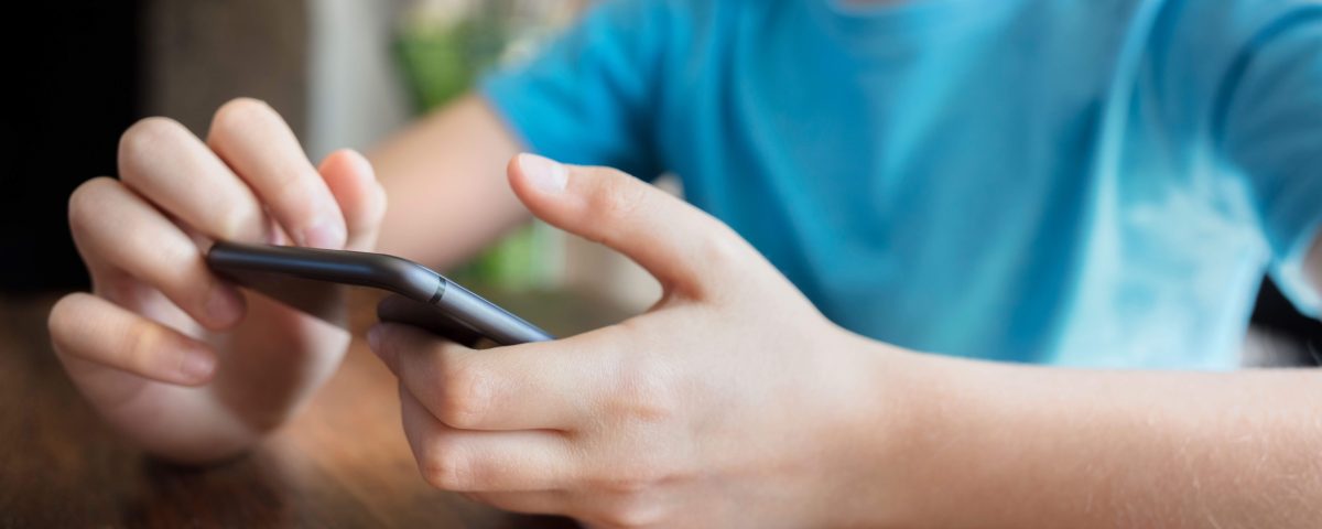 A child in a blue shirt on a smartphone.