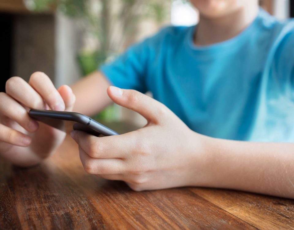 A child in a blue shirt on a smartphone.