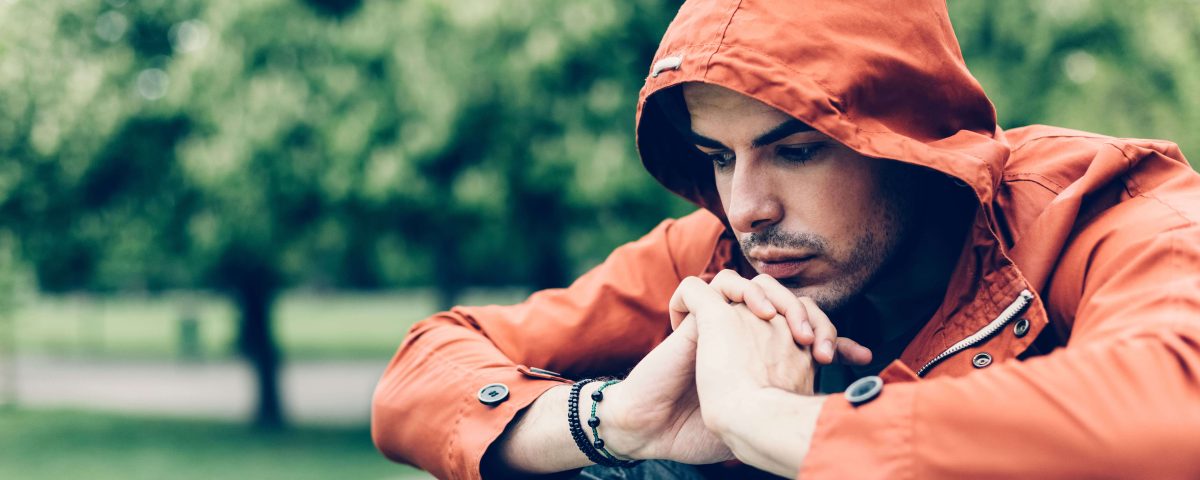 Man in an orange hoodie looking sad